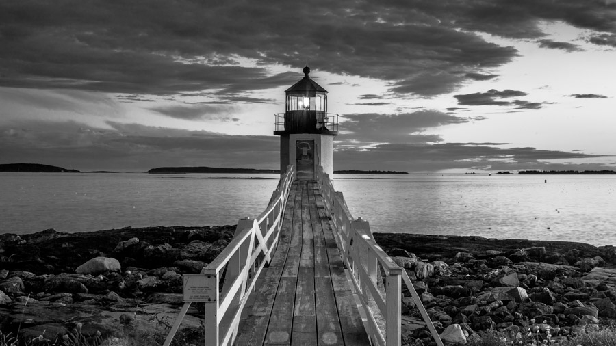 Image en noir et blanc d'un phare au bout d'un ponton face à la mer Image en noir et blanc d'un phare au bout d'un ponton face à la mer