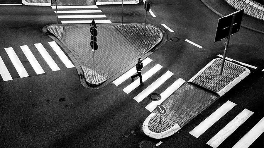 Black and white overhead image of a person in a crosswalk Black and white overhead image of a person in a crosswalk