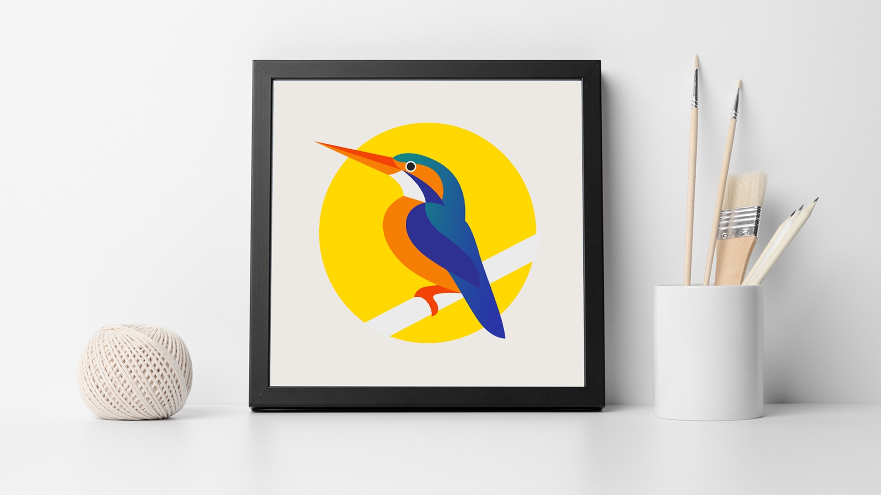 Auf einem Tisch steht ein eingerahmtes Bild von einem buntem Vogel in einem gelbem Kreis auf weißem Hintergrund. Auf einem Tisch steht ein eingerahmtes Bild von einem buntem Vogel in einem gelbem Kreis auf weißem Hintergrund.