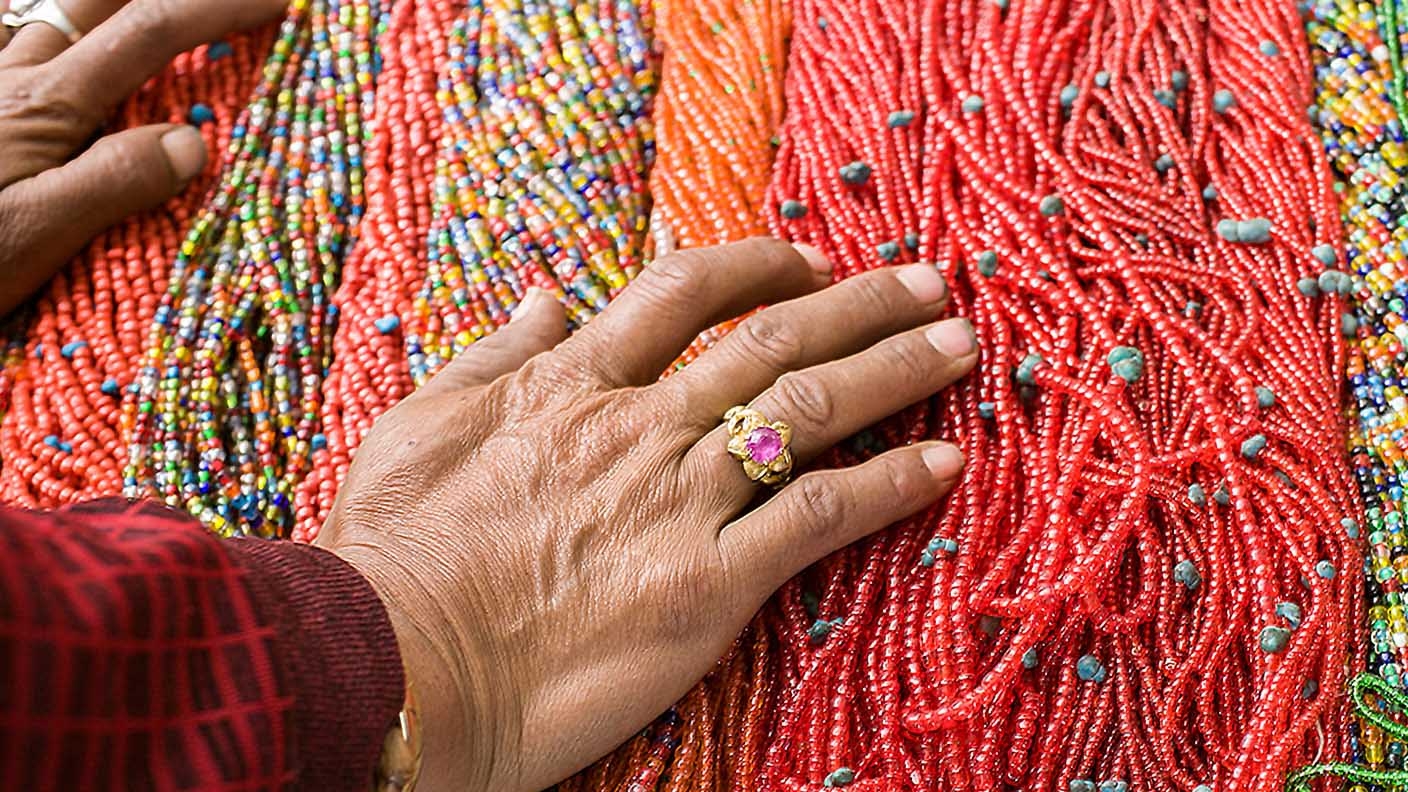 Woman’s hands spread across piles of multicolored bead strands
