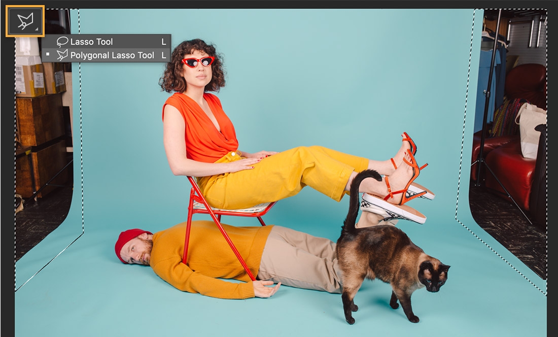 Two models and a cat pose on a teal backdrop, the studio appears on the left and right and the Lasso tool displays upper left Two models and a cat pose on a teal backdrop, the studio appears on the left and right and the Lasso tool displays upper left