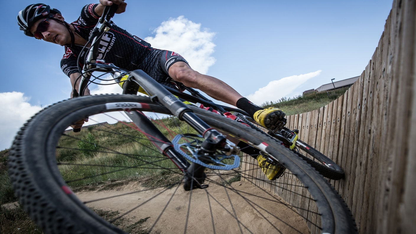 Extreme bicyclist rides his bike horizontally along a wooden fence. Extreme bicyclist rides his bike horizontally along a wooden fence.