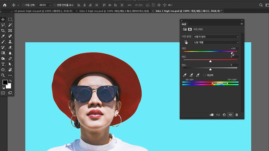 연한 파랑 배경에서 해를 보는 빨간 모자와 선글라스를 쓴 여성  